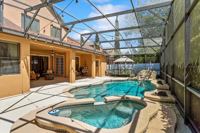 view of pool with a patio, fence, a pool with connected hot tub, ceiling fan, and a lanai