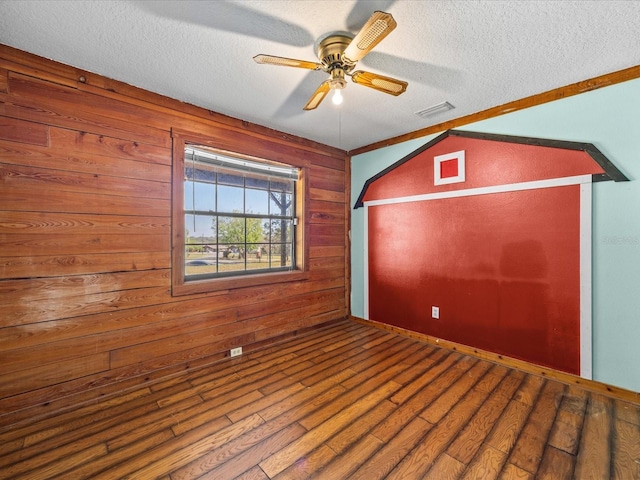 16510 Quarter Horse Ct, Montverde, FL 34756 - empty room featuring wood finished floors, wooden walls, a ceiling fan, and a textured ceiling