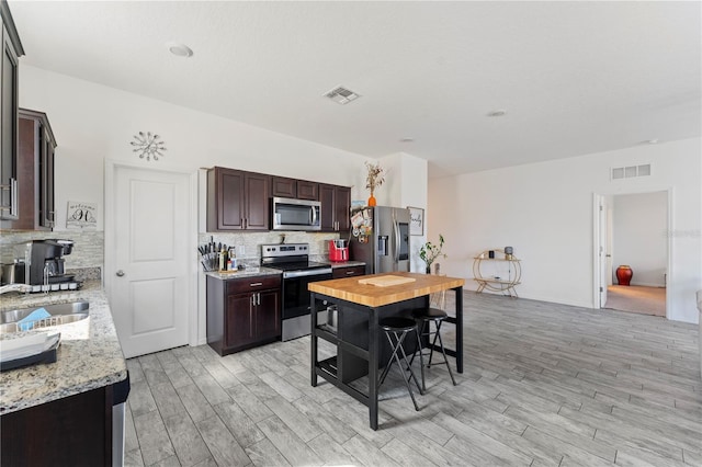 kitchen with dark brown cabinetry, visible vents, appliances with stainless steel finishes, and a sink