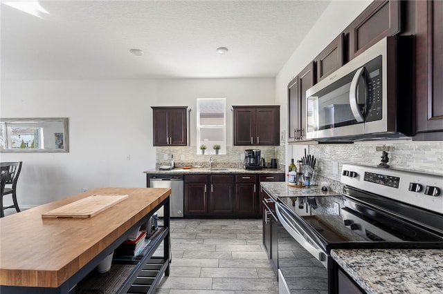 kitchen with stainless steel appliances, plenty of natural light, dark brown cabinetry, and decorative backsplash