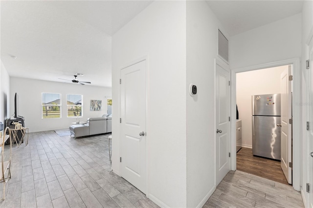 corridor featuring light wood-style floors, visible vents, and baseboards