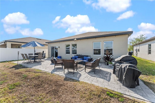 rear view of property with stucco siding, a patio, fence, a yard, and outdoor lounge area