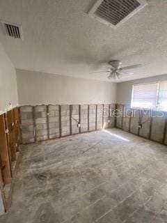 spare room with ceiling fan, visible vents, and a textured ceiling