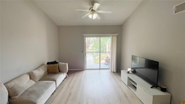 sitting room with a textured ceiling, a ceiling fan, visible vents, and light wood-type flooring