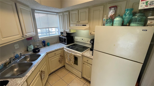 kitchen with under cabinet range hood, white appliances, light countertops, and a sink