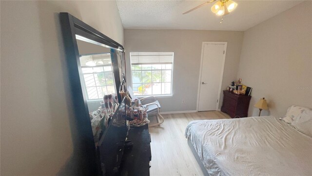 bedroom featuring ceiling fan, wood finished floors, baseboards, and a textured ceiling