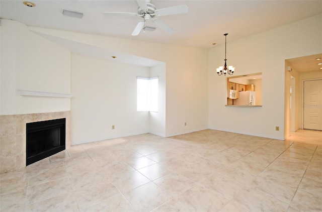 unfurnished living room featuring baseboards, lofted ceiling, a tiled fireplace, and ceiling fan with notable chandelier