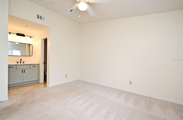 unfurnished bedroom with visible vents, baseboards, light colored carpet, ensuite bathroom, and a sink