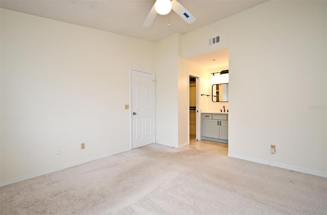 unfurnished room featuring visible vents, light carpet, a ceiling fan, a sink, and baseboards