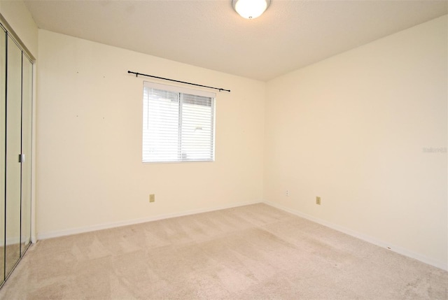 interior space with a closet, light carpet, and baseboards