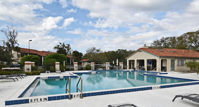 community pool with a patio area and fence