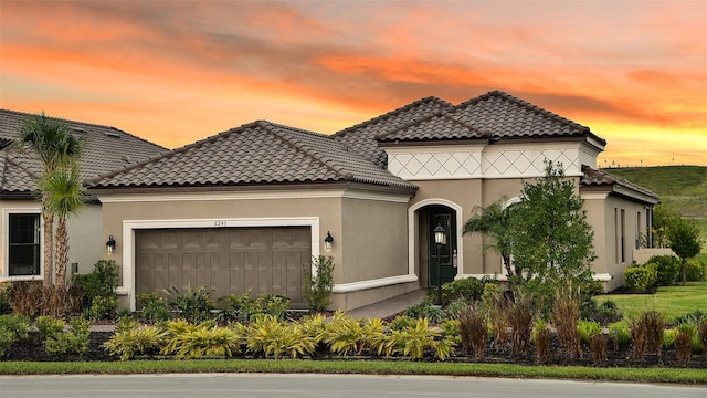 view of front facade with stucco siding, a tile roof, and a garage