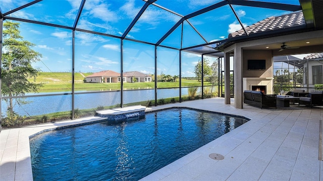 outdoor pool with a lanai, a patio area, a large fireplace, and a water view