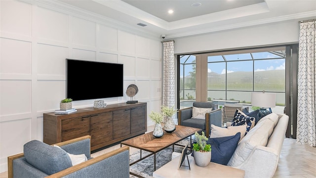 living area featuring recessed lighting, a tray ceiling, crown molding, and a decorative wall