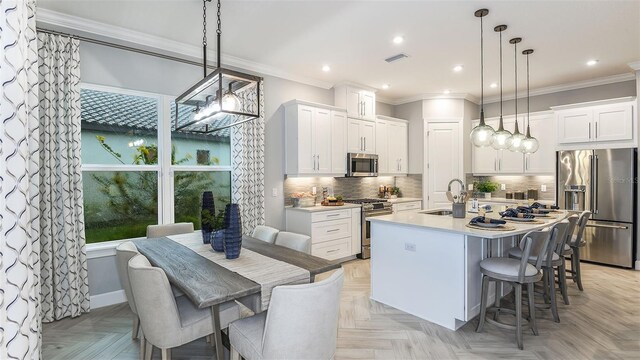 kitchen featuring high end appliances, visible vents, a center island with sink, a sink, and light countertops