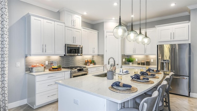 kitchen with a sink, crown molding, a breakfast bar, appliances with stainless steel finishes, and a kitchen island with sink