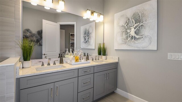 bathroom featuring double vanity, baseboards, and a sink