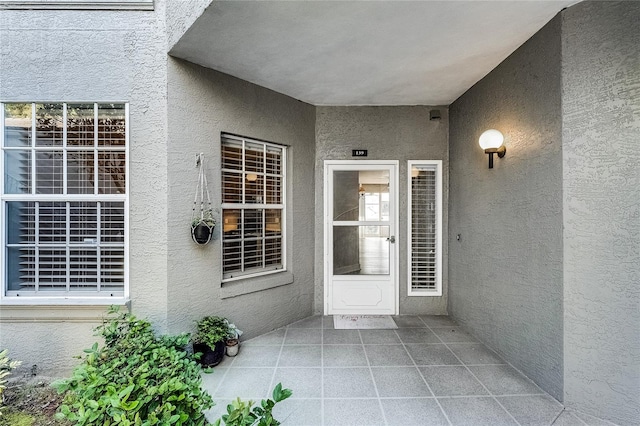 view of exterior entry featuring a patio area and stucco siding