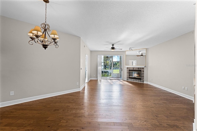 unfurnished living room featuring a textured ceiling, a fireplace, dark wood-style flooring, and ceiling fan with notable chandelier