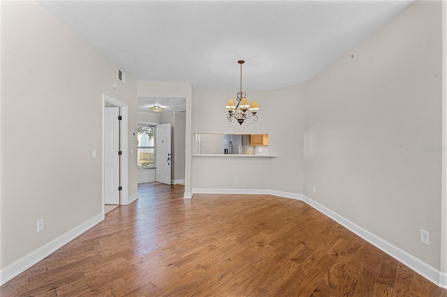 interior space with an inviting chandelier, wood finished floors, visible vents, and baseboards