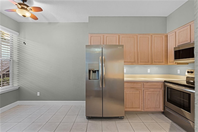 kitchen with a ceiling fan, light brown cabinetry, stainless steel appliances, light countertops, and light tile patterned floors