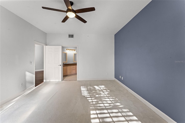 unfurnished bedroom with visible vents, baseboards, light colored carpet, and ensuite bathroom