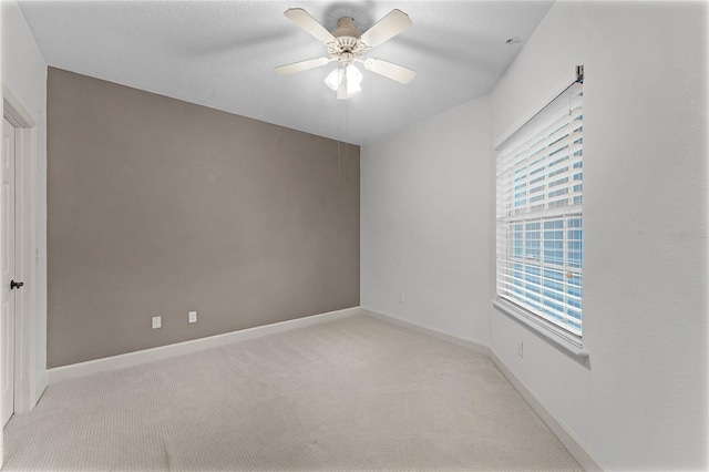 spare room featuring baseboards, light carpet, and a ceiling fan