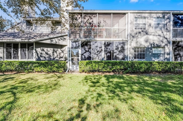 rear view of property with a yard and a sunroom