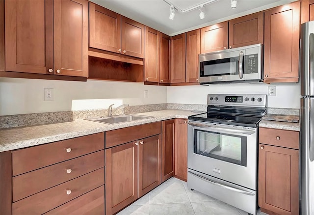 kitchen with light countertops, light tile patterned floors, appliances with stainless steel finishes, and a sink