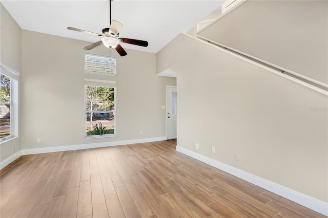 unfurnished living room featuring a wealth of natural light, baseboards, light wood-style flooring, and ceiling fan