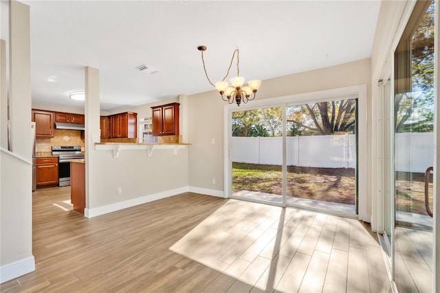 interior space with light wood-style flooring, visible vents, baseboards, and a chandelier