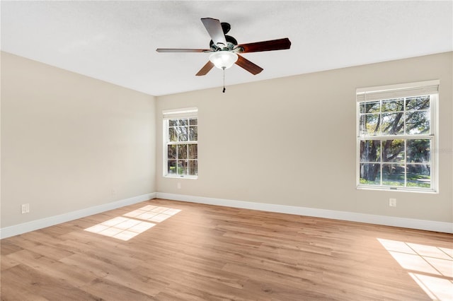 empty room with a healthy amount of sunlight, baseboards, and light wood-style floors