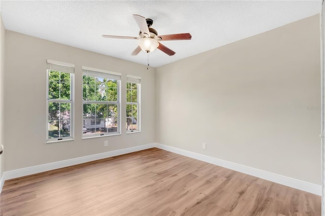 empty room featuring baseboards, light wood-style floors, ceiling fan, and a textured ceiling