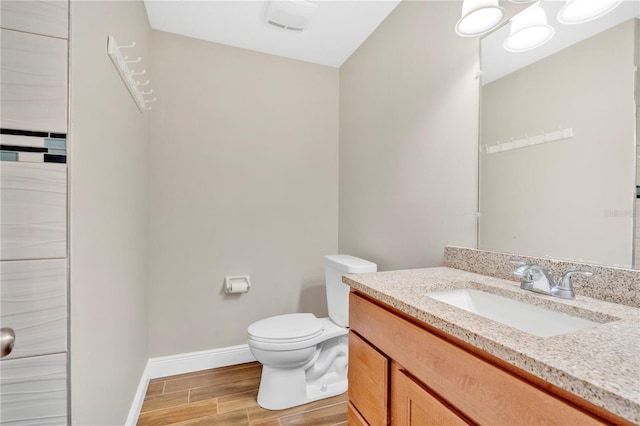 bathroom featuring wood finish floors, baseboards, toilet, and vanity