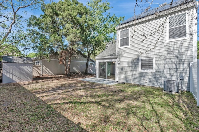 rear view of property with central air condition unit, an outbuilding, fence, a yard, and a storage shed