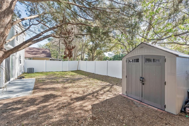 view of yard with a storage unit, central air condition unit, an outbuilding, and a fenced backyard