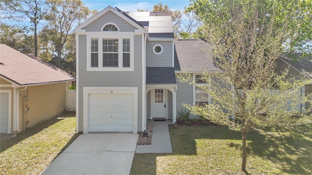 traditional-style house with a garage, driveway, a shingled roof, and a front lawn