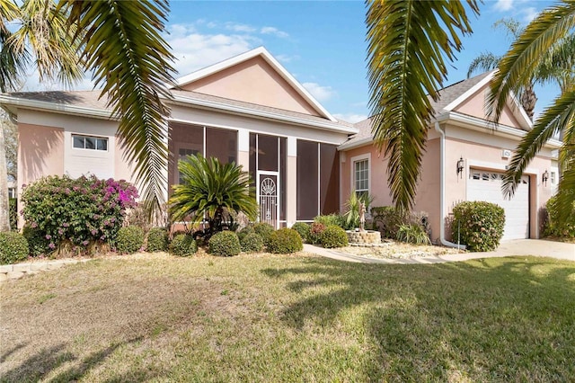 view of front facade featuring stucco siding, an attached garage, a front lawn, and a sunroom