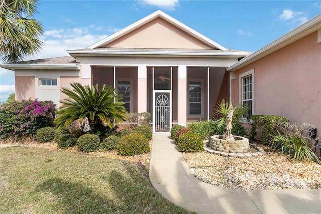 view of front facade with stucco siding and a sunroom