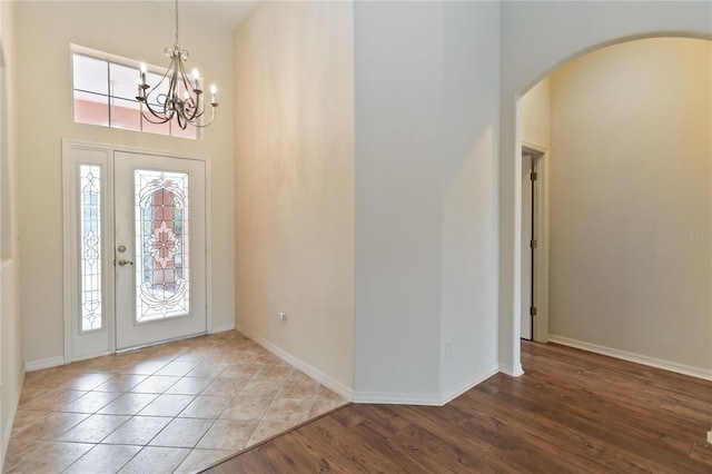 entryway featuring wood finished floors, plenty of natural light, arched walkways, and a towering ceiling