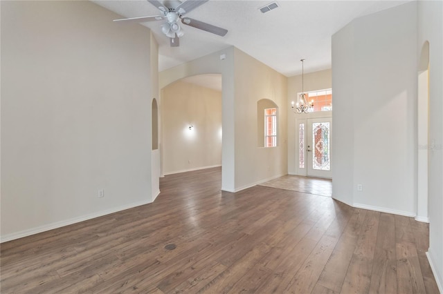 unfurnished room with visible vents, ceiling fan with notable chandelier, hardwood / wood-style floors, arched walkways, and baseboards