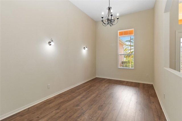 spare room with baseboards, wood-type flooring, and a chandelier