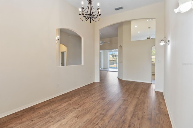 spare room with a notable chandelier, visible vents, baseboards, and wood-type flooring