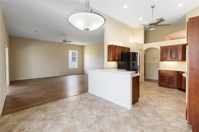 kitchen featuring black fridge, open floor plan, arched walkways, light countertops, and ceiling fan