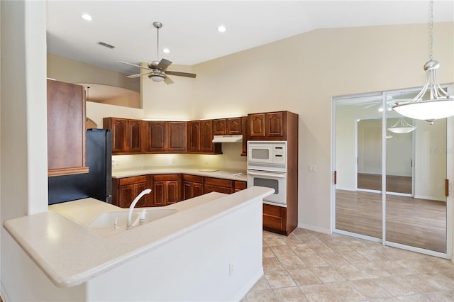 kitchen featuring visible vents, a sink, white appliances, a peninsula, and light countertops