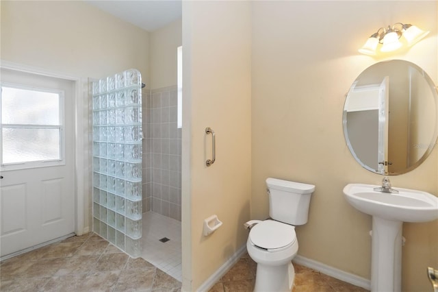 bathroom with tile patterned floors, toilet, a walk in shower, a sink, and baseboards