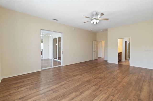 empty room with visible vents, wood finished floors, baseboards, and ceiling fan