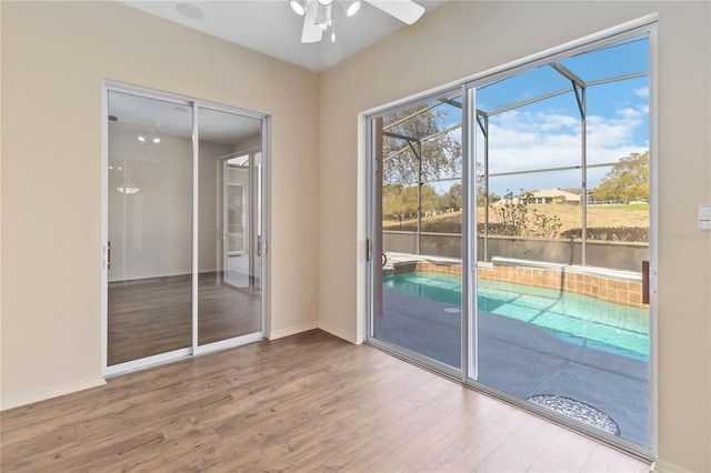 interior space featuring a ceiling fan, baseboards, and wood finished floors