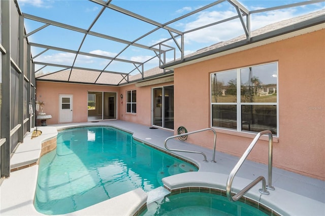 view of swimming pool featuring a patio area, glass enclosure, and a pool with connected hot tub