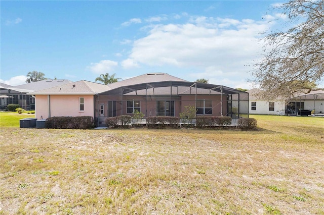 back of house with a yard, central air condition unit, a lanai, and stucco siding